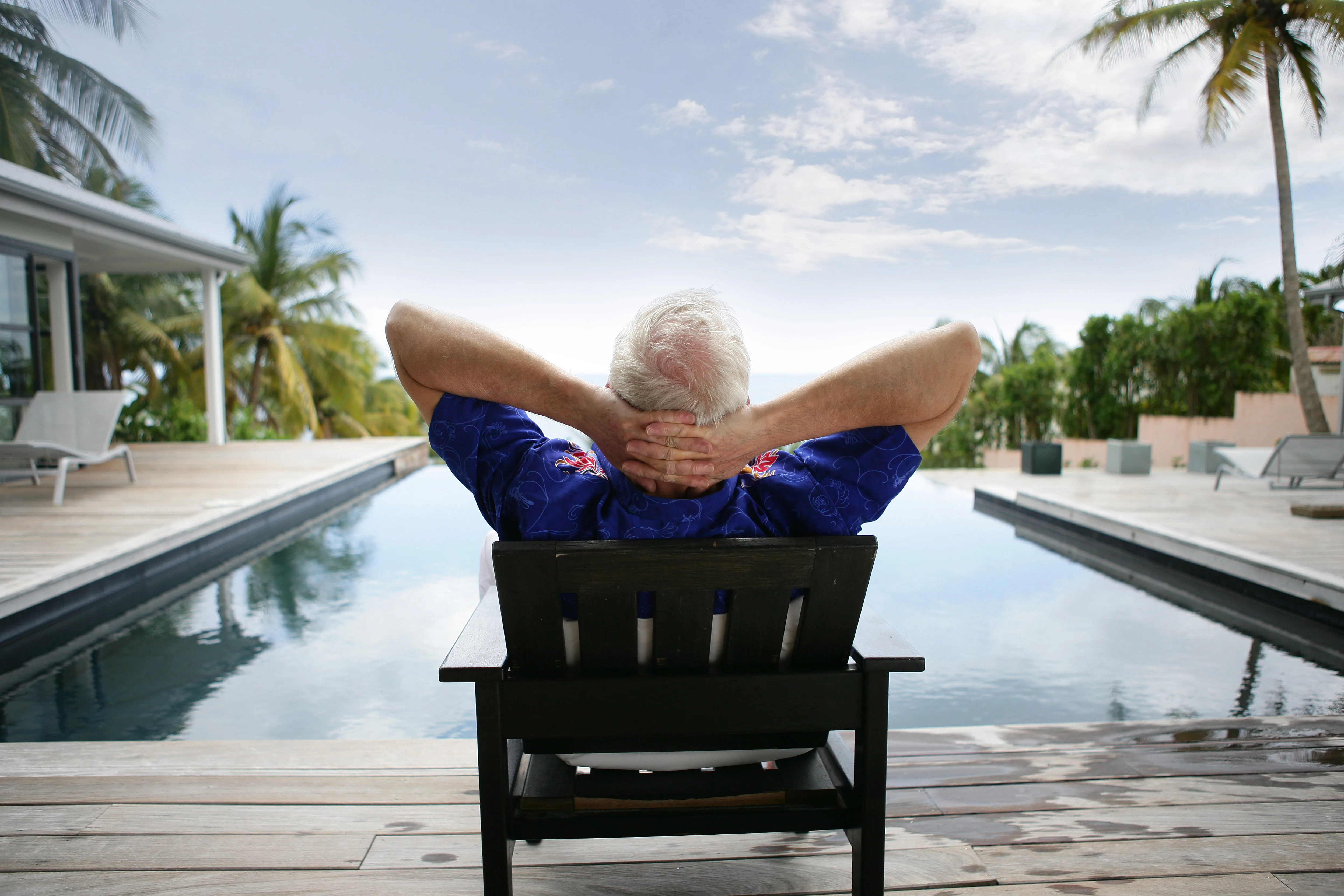 Homme âgé assis sur une chaise au bord d'une piscine Homme âgé assis sur une chaise au bord d'une piscine